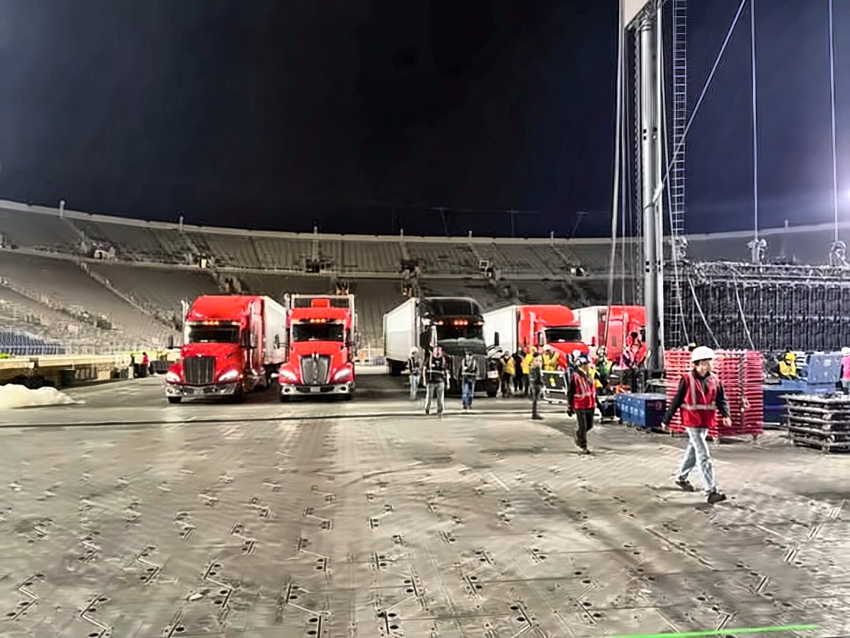 Stadium concert load-in with trucks, trailers and crew